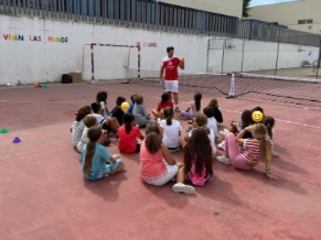 Clase de pickleball con un grupo de niños sentados en la pista
