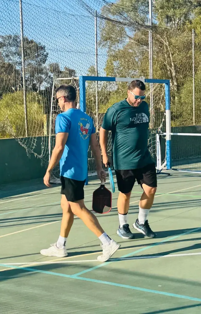 Dos jugadores caminando por la pista con sus palas