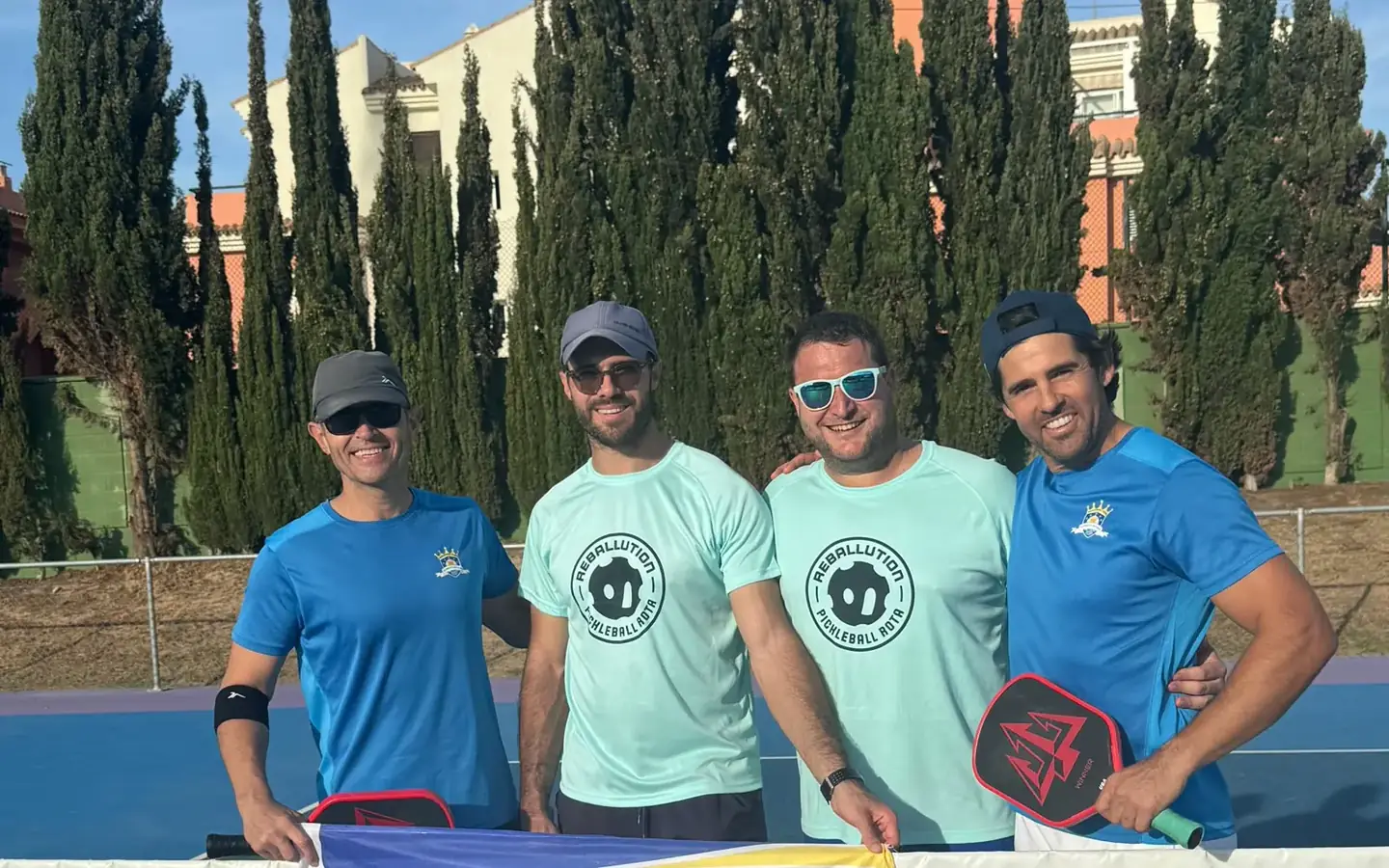 Jugadores del club sujetando la bandera de El Puerto Pickleball Club en la pista